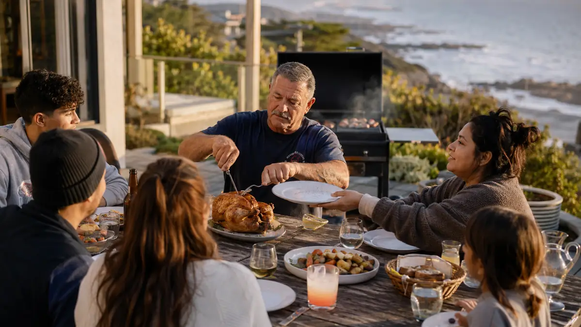 A family gathered around a patio table carving a whole roasted chicken fresh off the grill
