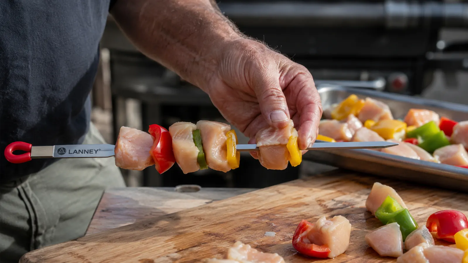 Hand threading chicken and pepper chunks onto a LANNEY flat stainless skewer